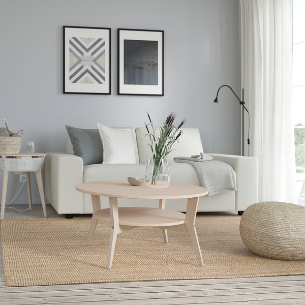 Modern living room with sleek JAKOBSFORS light wood coffee table, round, white couch, blue wall, and natural decor.