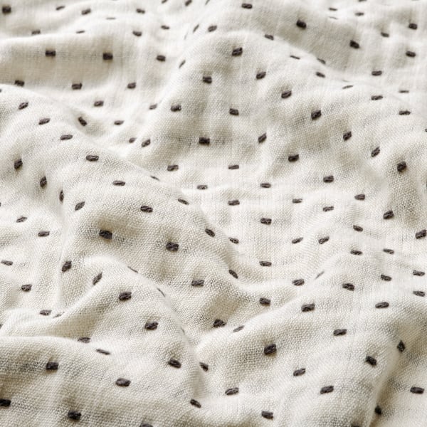 Close-up of a soft, white cotton blanket with even, decorative grey stitching, highlighting its natural and durable quality.