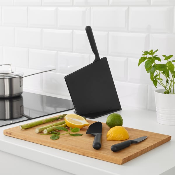 Black JÄMFÖRA knives on wooden board with sliced fruits/veg; one in block.