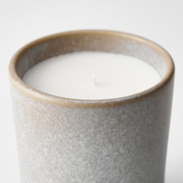 Cylindrical stoneware candle with smooth, layered glaze. White wax interior with single wick, sits on plain background.