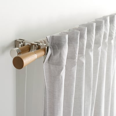 Closeup of curtain rod with light fabric. Shows rods oak finials and metal brackets.