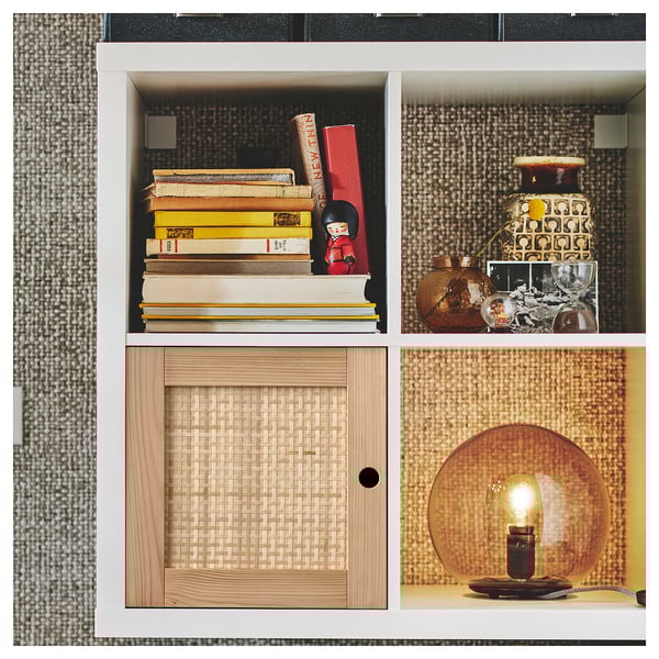 KALLAX shelf with books, decor, wicker door, gold lamp.