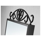Black decorative mirror with ornate top crown detail, reflective surface, and small storage tray below. Ideal for bathroom or bedroom use.
