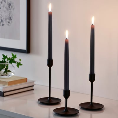 Eight black KLOKHET candles, slim, cylindrical shape, made of stearin.