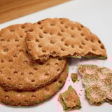 Stacked whole grain crispbreads, some broken, on white surface.