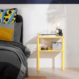 Yellow side table beside bed with lamp & decor. Modern, lightweight, easy assembly.