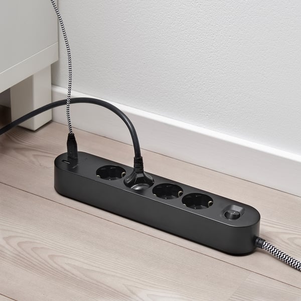 Black multi-socket with usb ports on wooden floor.