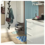 Modern hallway with hooks holding jacket, bag, and mat on wooden floor.