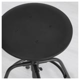 Black round stool with adjustable feet, manufactured with metal and wood. Shown in a minimalist setting.