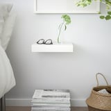 White LACK shelf with glasses, vase, and greenery, plus magazines and tissues. Neutral, organized space.