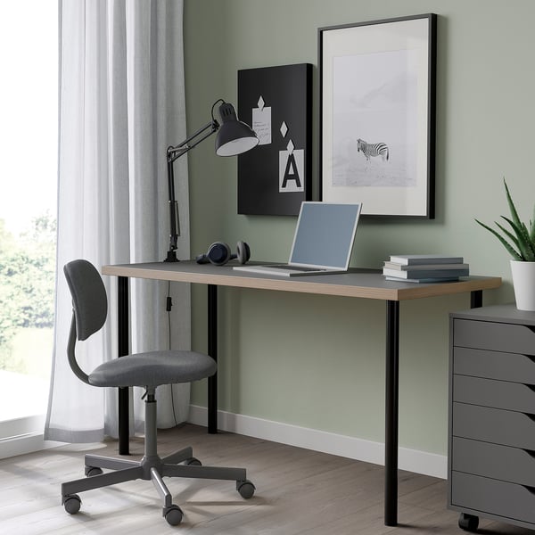 LAGKAPTEN desk: sleek black, modern design. Laptop & books fit well. Grey chair and lamp nearby. Decorative art on wall.