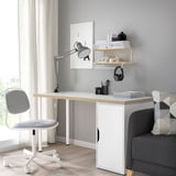 Home office setup with LAGKAPTEN white desk, grey chair, grey couch, wooden floors, shelves with books and decor, and light-colored curtains.