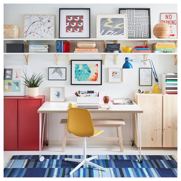 Bright home office setup with light wood desk, yellow chair, colorful art, and blue rug. Modern and fresh design.