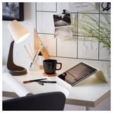 Minimalist desk setup with white LAGKAPTEN table, lamp, tablet, black mug, pens, and plant.