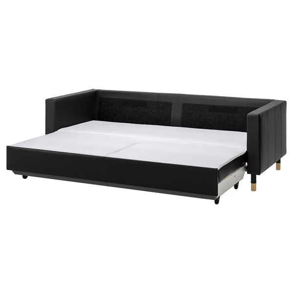 Black convertible sofa with treats leather, metal legs, and back cushions, designed for comfort and storage.