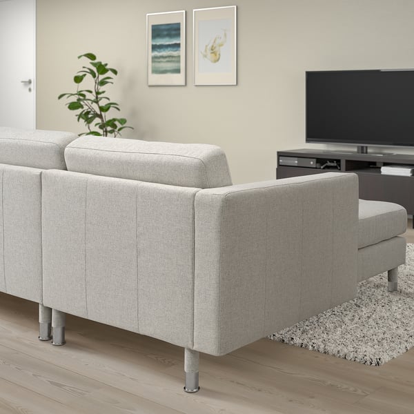 Modern gray 3-seat sofa in living room with metal legs, cushioned seats, rug, tv, plant.