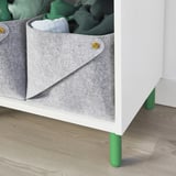 White storage unit with gray fabric bin and green legs on wooden floor.