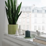 Green LÄTTNAD candle with lime holder and white deco, stacks of books nearby.