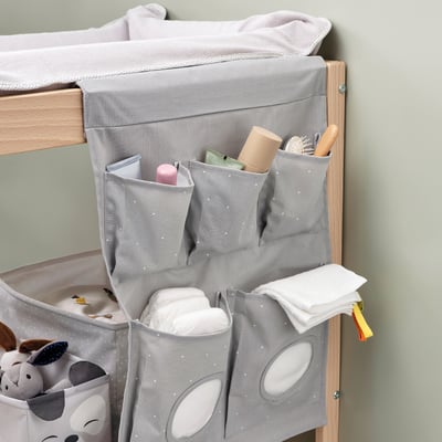 Gray hanging organizer on wooden frame, holding toiletries and cloths.