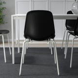 Black stacking chair with white legs, suitable for home use.