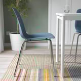Chromed metal base chair, blue seat shell, stackable and flexible design, suitable for indoor use.
