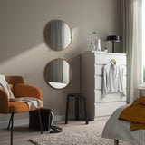 Modern bedroom with gold mirrors, orange chair, & yellow bed blanket.