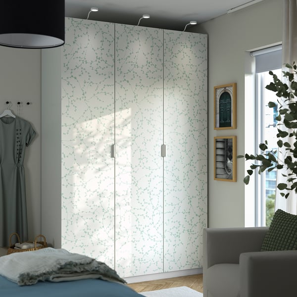 Large white LINNABERG cabinet with green leaf pattern. Tall, narrow, fits between bed & gray couch.