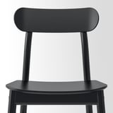 Black wooden chair with smooth, curved backrest and seat, shown from the back. Simple, sturdy design.