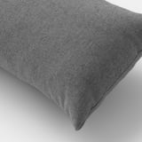 Close-up of a soft, grey, recycled fabric cushion, resting on a plain surface, showcasing its plush texture and fine stitching.