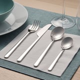 A silverware set laid out on a placemat includes a fork, knife, large spoon, and small spoon, arranged neatly for use.