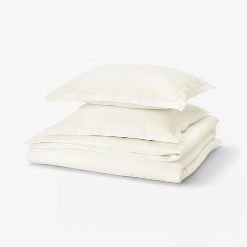 Folded white cotton duvet set with waffle weave, neatly stacked, atop light background.