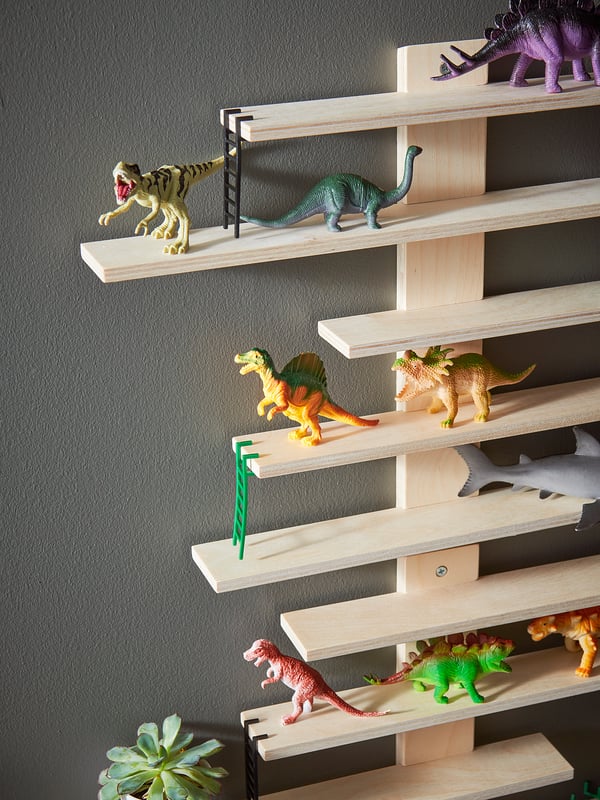 Wooden wall shelves, LUSTIGT, in natural color with adjustable ladders. Displaying toy dinosaurs, with a succulent plant at the bottom.