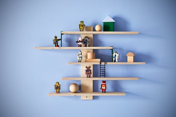 Wooden wall shelf lined with small ladders, displaying colorful toy robots on multiple sliding shelves, against a light blue wall.