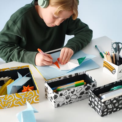 Four colorful, patterned storage boxes in yellow, white, and black; designed with abstract shapes, perfect for organizing items.
