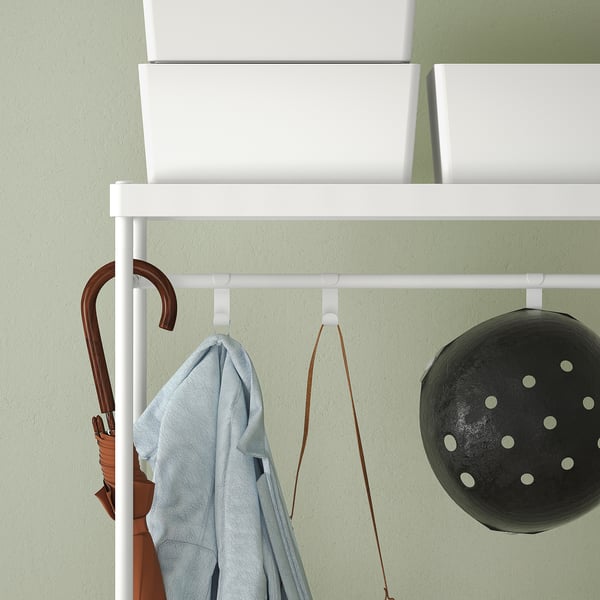 Wall-mounted coat rack with hooks and shelf, holding umbrella and basket.