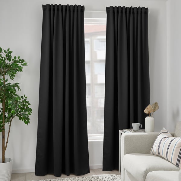 Modern living room with tall black MAJGULL curtains, white couch, small table, and potted plant. Curtains are long, covering the window fully.
