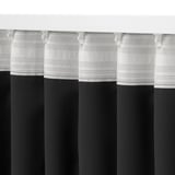 Black-out curtains hung high, with pleated folds and hooks, blocking light and offering privacy.