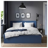 Blue MALM bed, white linens, framed photos, lamps, door open, throw blanket, plant, rug.