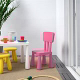 Bright pink MAMMUT kids chair near table with cups.