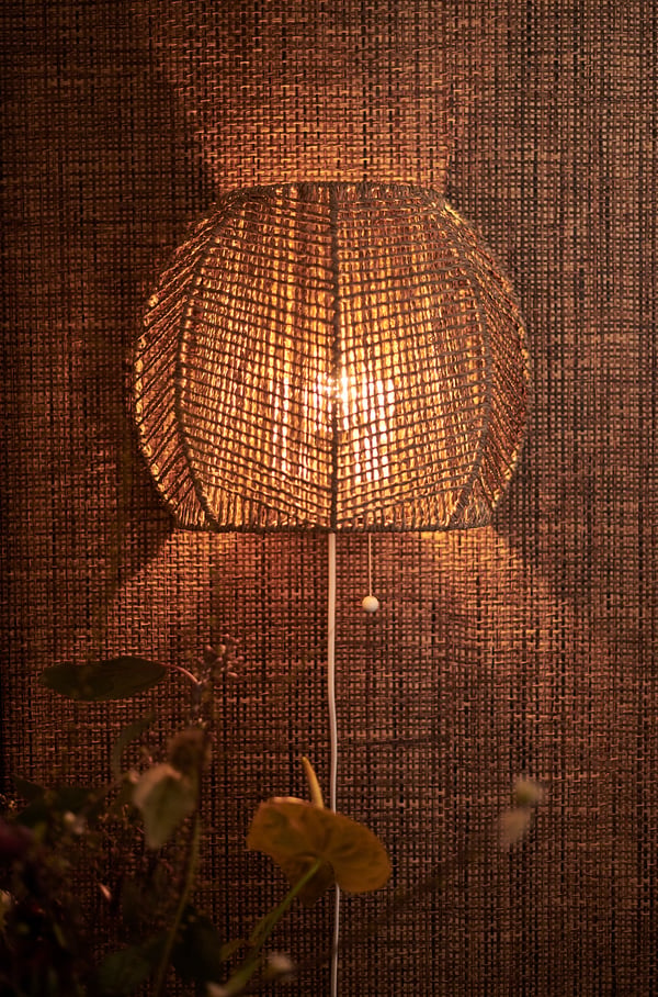 An illuminated, hand-braided lamp with warm, golden light. Made of natural sedge, unique in design with a pull cord.