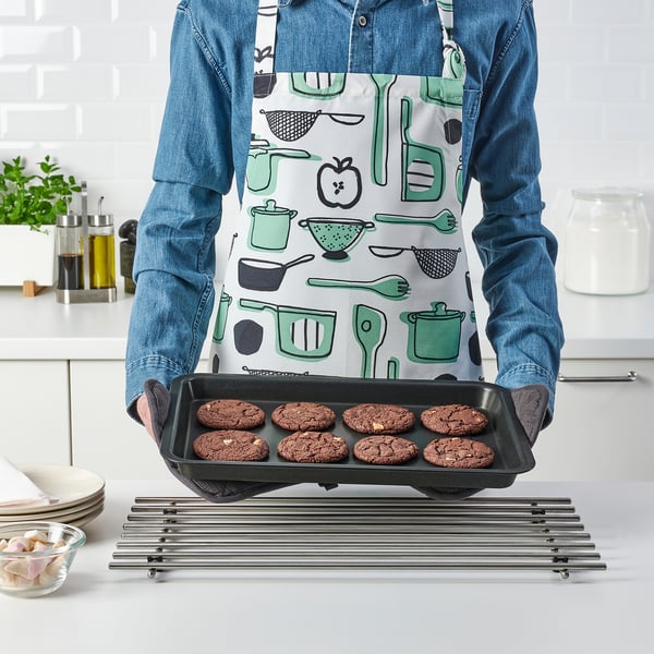 Person holding a baking tray with cookies in a kitchen.