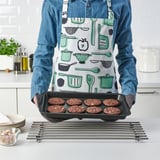 Person holding a baking tray with cookies in a kitchen.