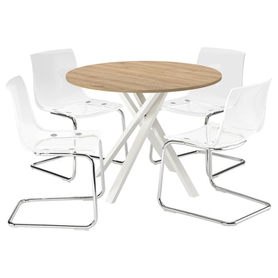 A modern dining set called MARIEDAMM with a round wooden table and four clear plastic chairs with chrome legs.