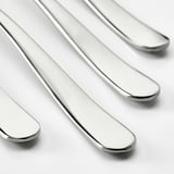 Four sleek, polished silver forks arranged closely together, highlighting their smooth, reflective surfaces and elegant curves.