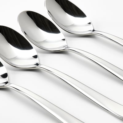 Four gleaming, polished stainless steel spoons arranged neatly in a row, reflecting light, showcasing high-quality craftsmanship.