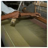 Hands weaving green and navy striped fabric on a loom.