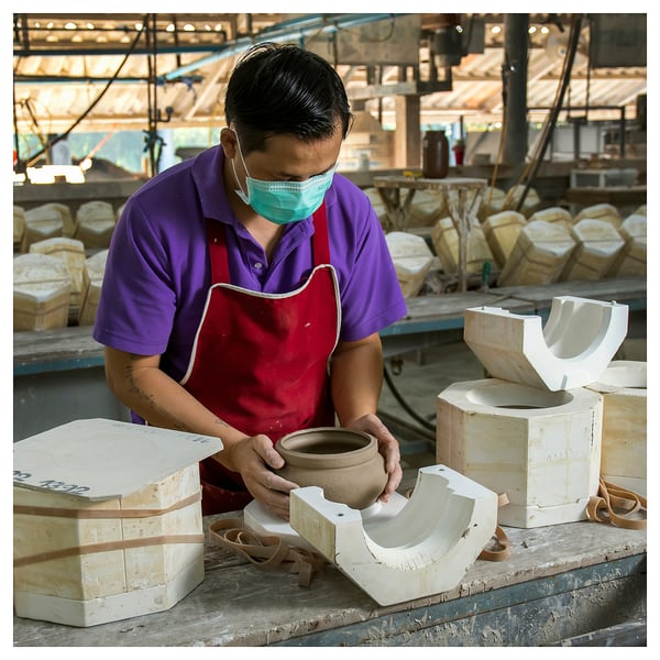 Man crafting a bowl at workshop bench.