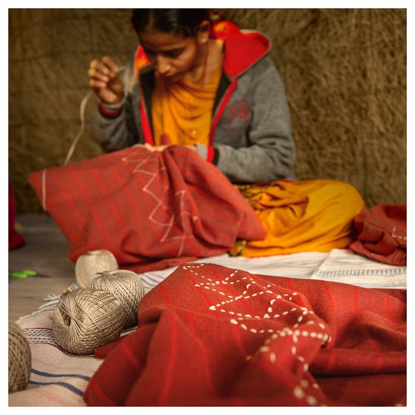 Woman crafting with MÄVINN red striped cotton cushion covers.