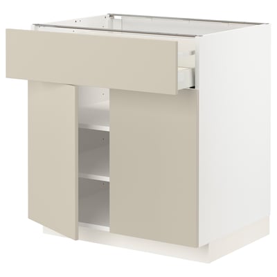 White METOD kitchen unit with beige drawer and shelves.