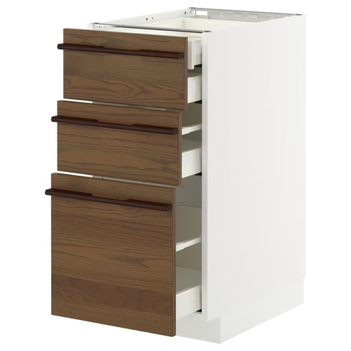 A METOD kitchen unit with dark brown stained ash veneer drawers and wooden handles. Its white with three pull-out drawers.